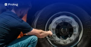 Um homem agachando fazendo a calibração do pneu de um caminhão.